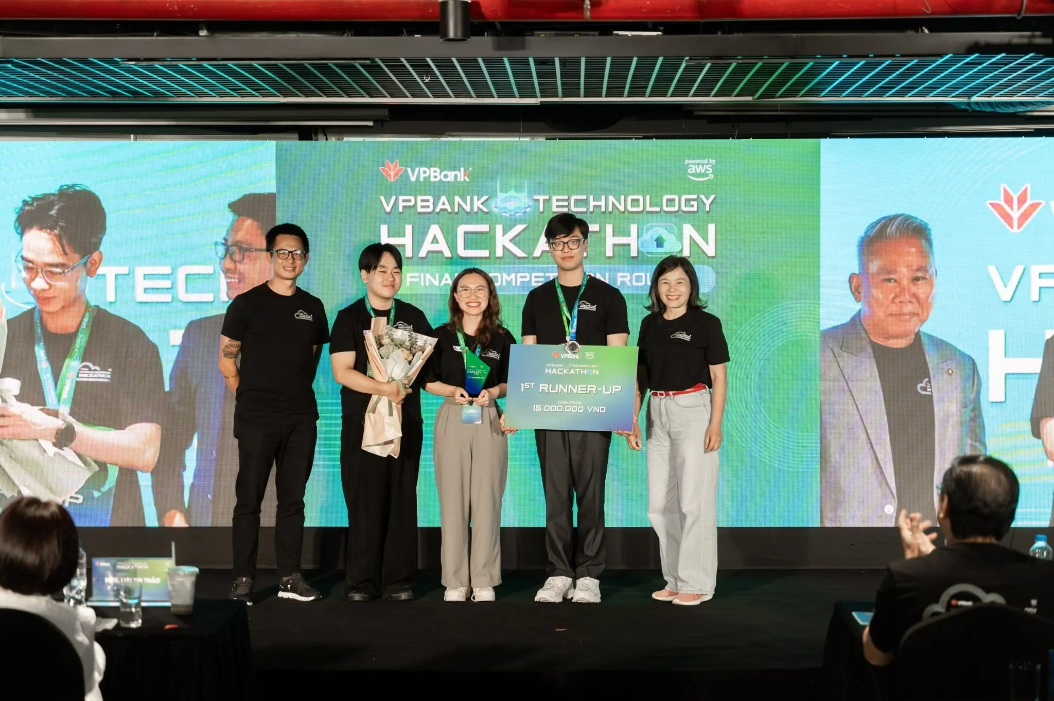 Năm người đứng trên sân khấu lễ trao giải, cầm tấm bảng ghi 1ST RUNNER-UP — 15.000.000 VND, phía sau là màn hình VPBank Technology Hackathon Final Competition Round